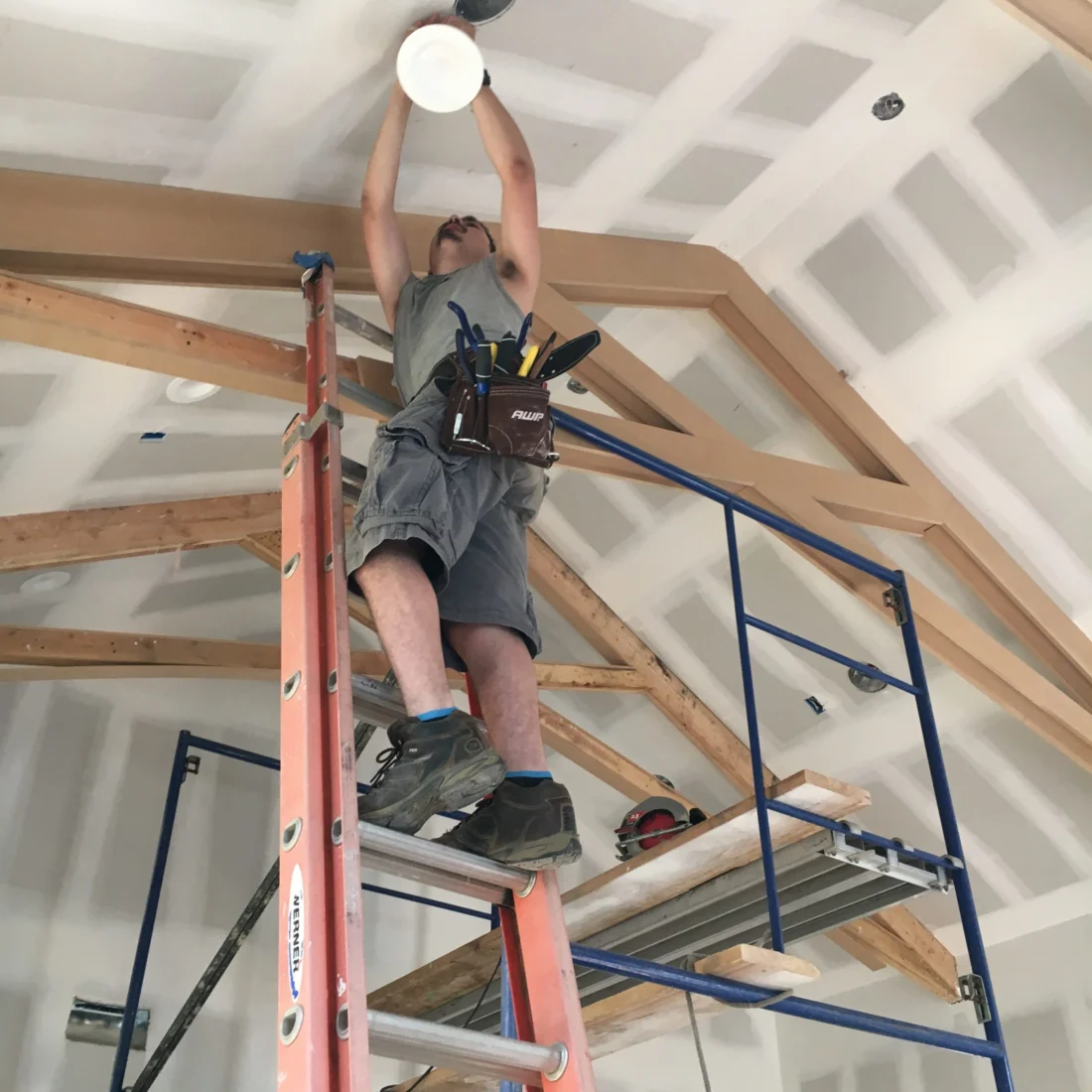 Electrician working on ceiling wiring from a scaffold