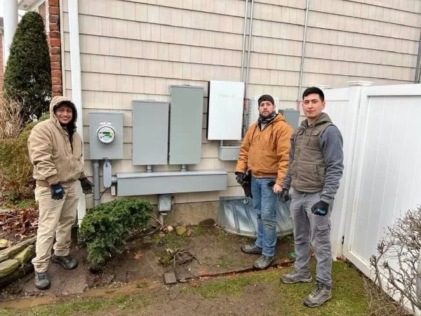Three workers beside exterior electrical service equipment